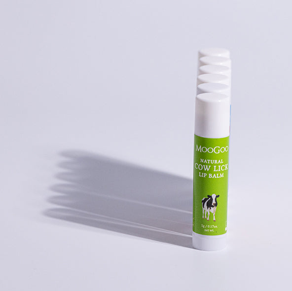 straight line of MooGoo Cow Lick Lip Balm on plain background, natural lip moisturiser with edible ingredients for smooth soft lips, petroleum free, all natural