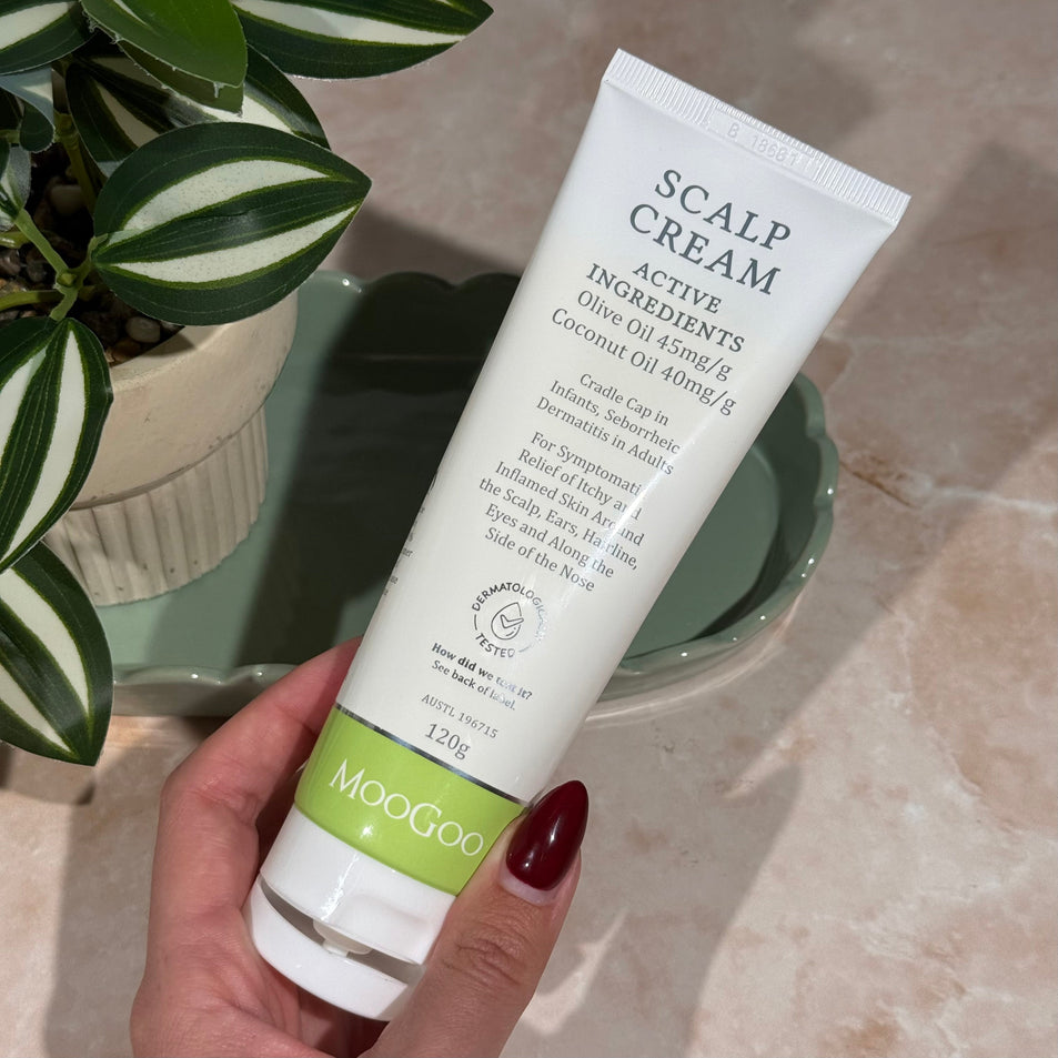 Hand holding MooGoo Scalp Repair Cream tube, natural cream for seborrheic dermatitis and psoriasis